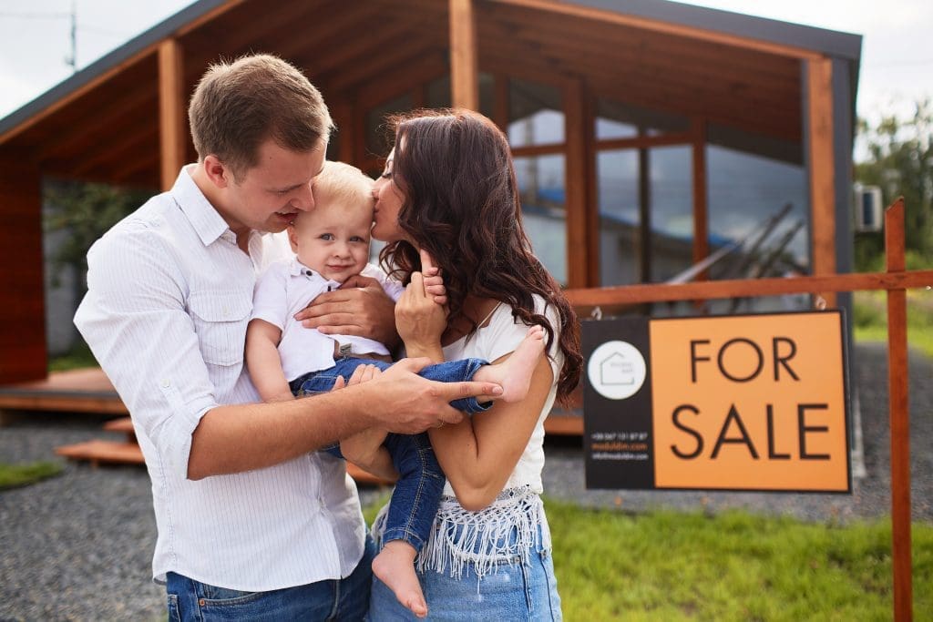 Family embracing in front of their new lease to own home