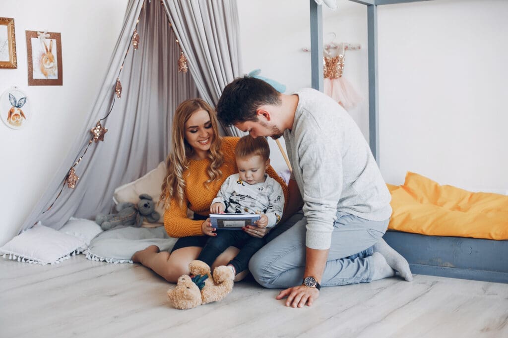 A loving couple with their child, reading a book together in their child's cozy room. This heartwarming moment captures the joy and stability that first time homebuyers can experience through a lease to own program, creating the perfect space for their growing family.