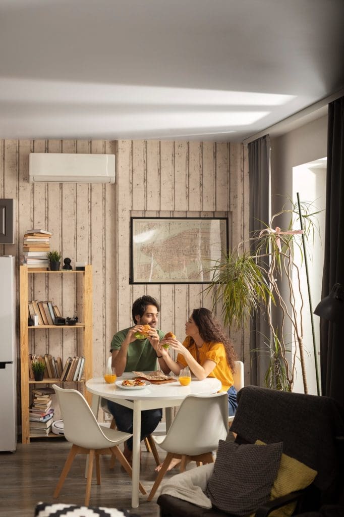 A happy couple dining at home, seated at a modern dining table with a warm, inviting ambiance. Enjoying the comfort of their new lease to own home in Raleigh NC