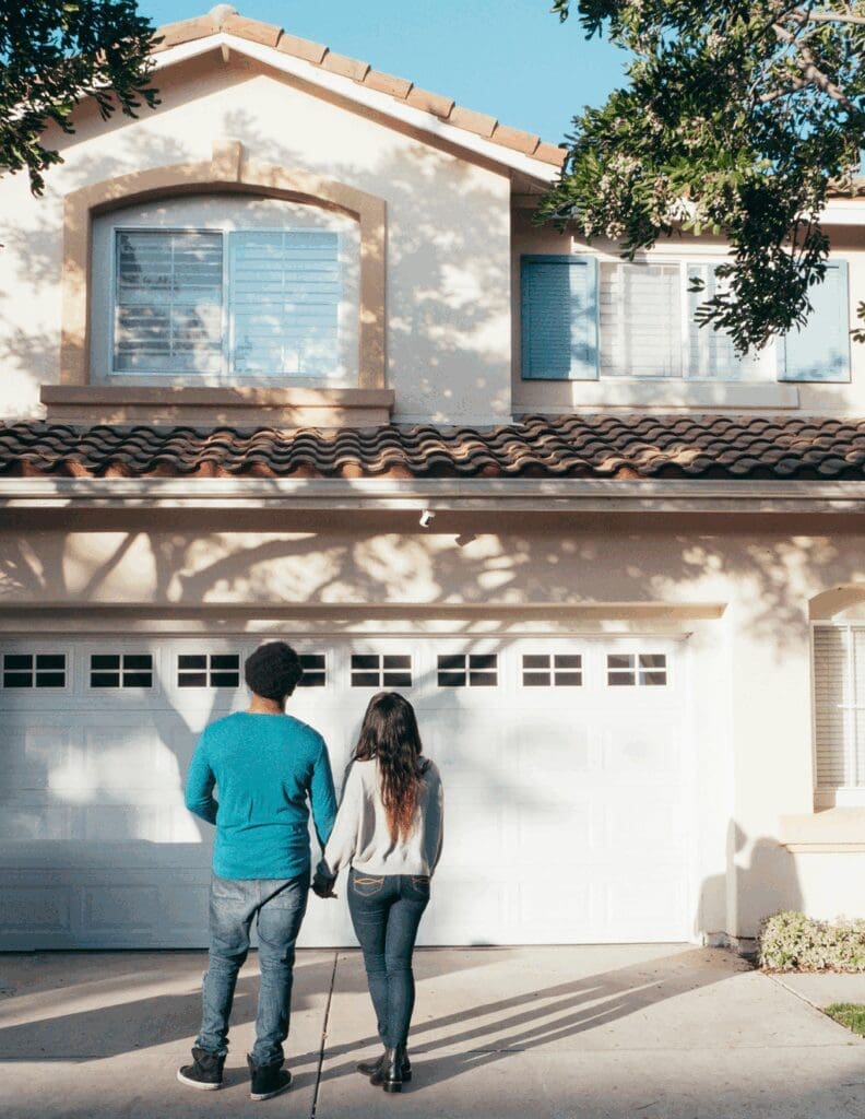 Young couple standing confidently in front of their new home, symbolizing alternative paths to homeownership—such as Lease-to-Own Raleigh—in 2025 without a traditional mortgage.